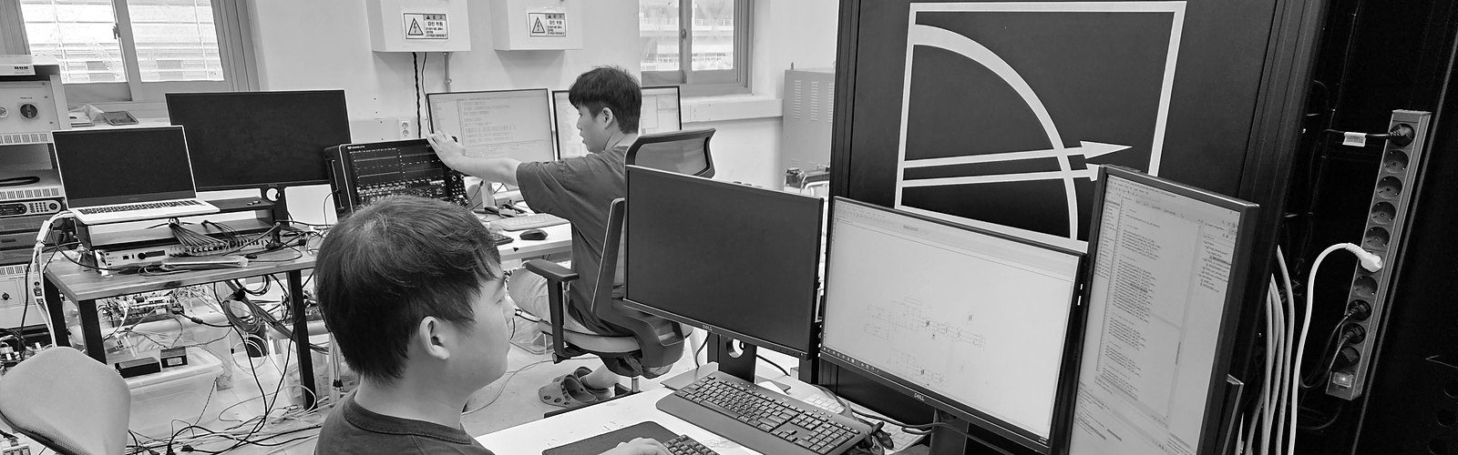 Two lab members: one at the real-time simulator, one at the hardware bench